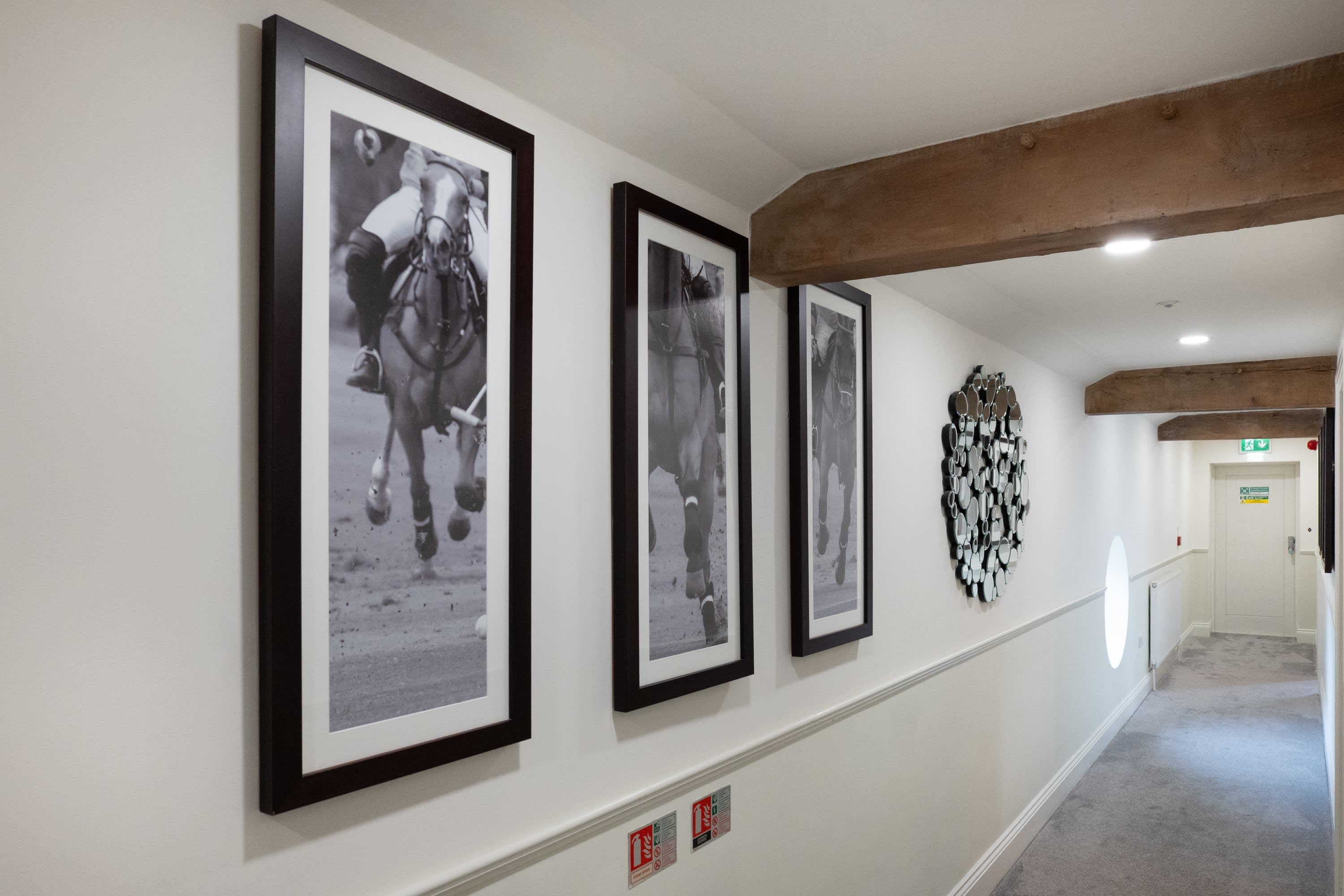 Merrydale Manor hotel corridor featuring large-format black and white equestrian photography prints beneath exposed timber beams