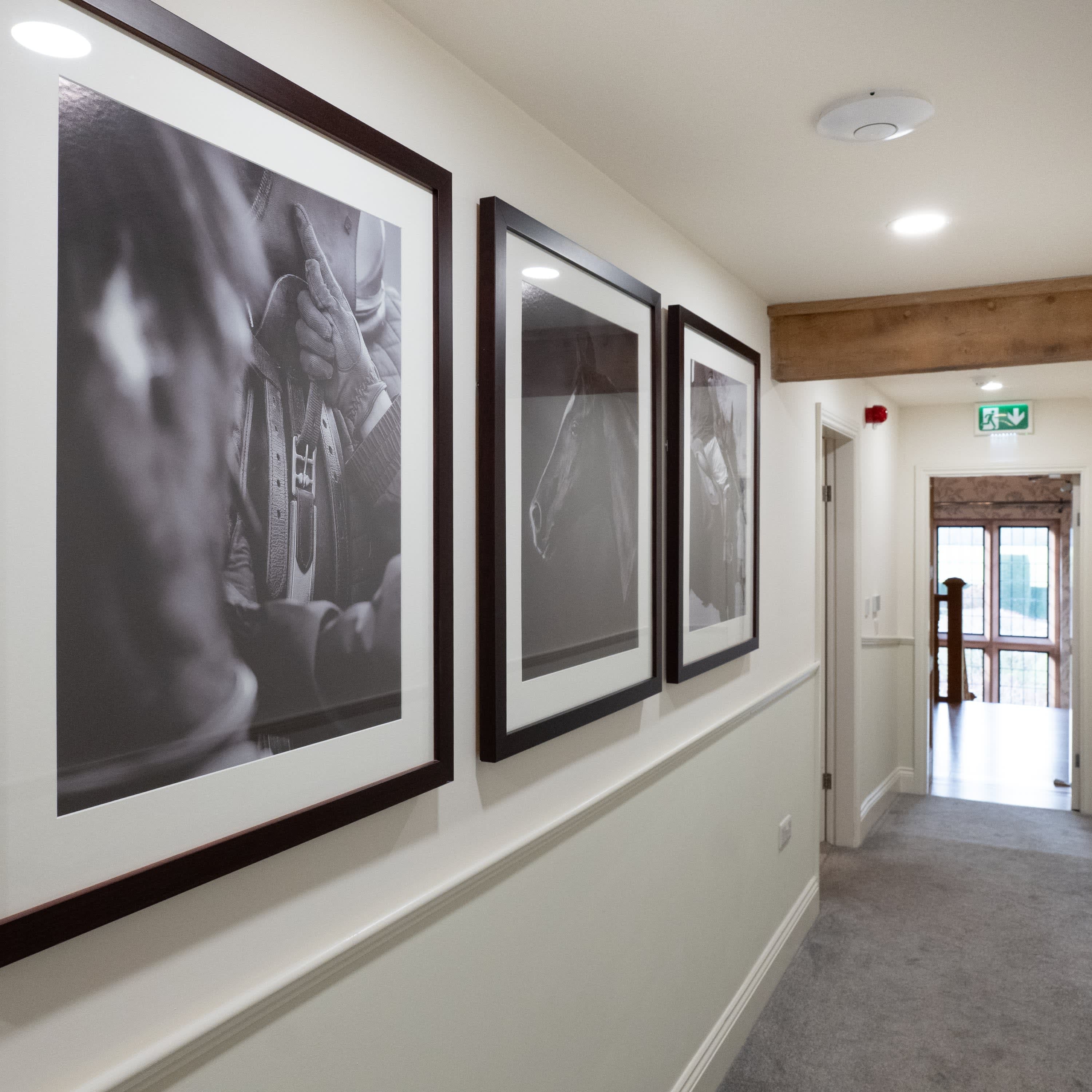 Merrydale Manor hallway lined with framed black and white photography prints leading to natural light at corridor end
