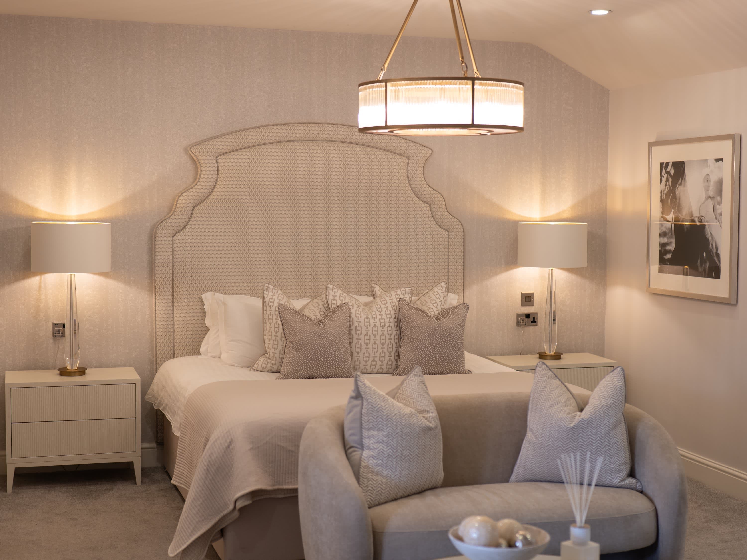 Full view of Merrydale Manor luxury suite showing pendant chandelier, curved seating area and dressed king-size bed