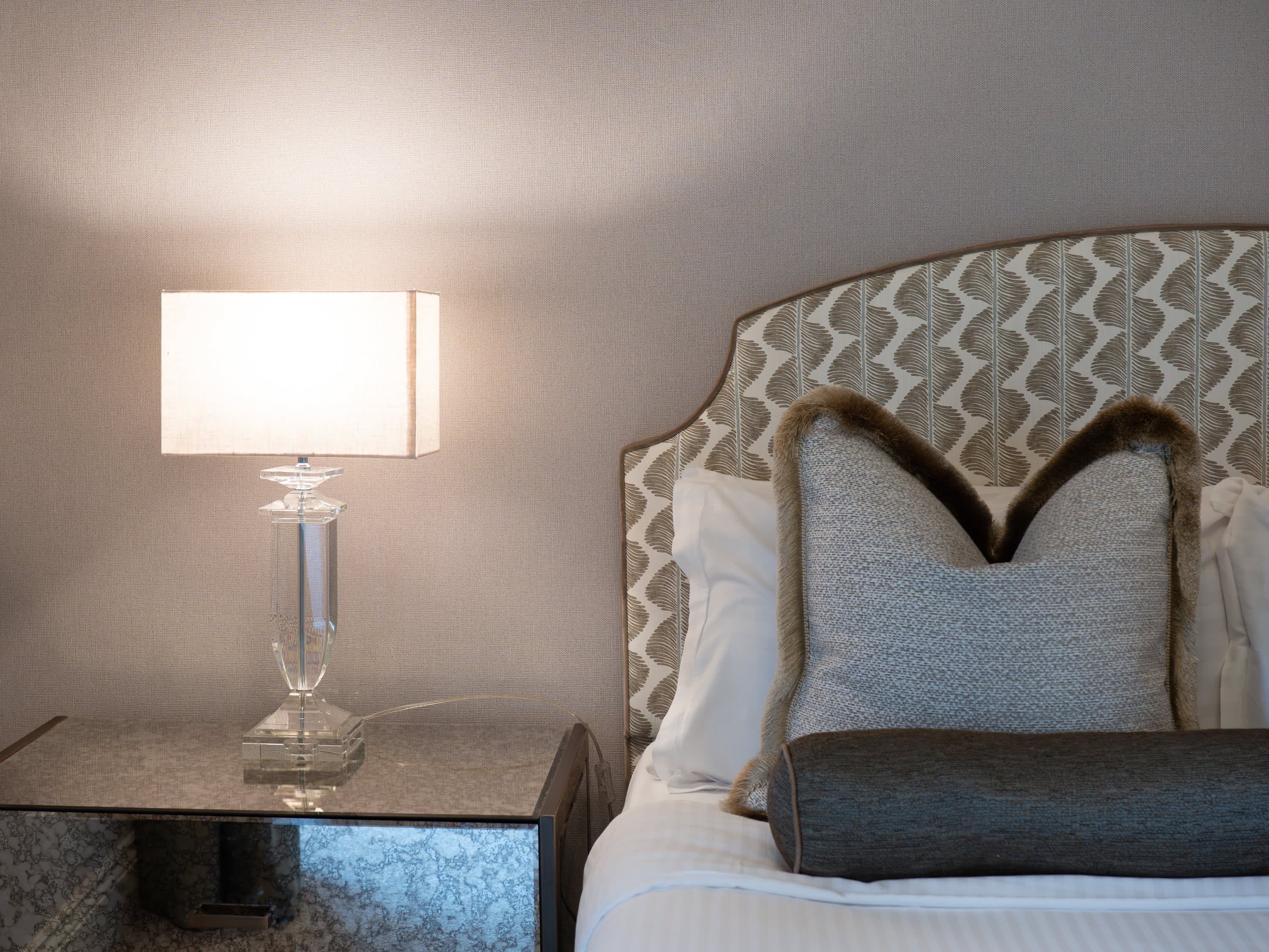 Merrydale Manor bedroom with crystal glass table lamp on mirrored bedside table and patterned upholstered headboard