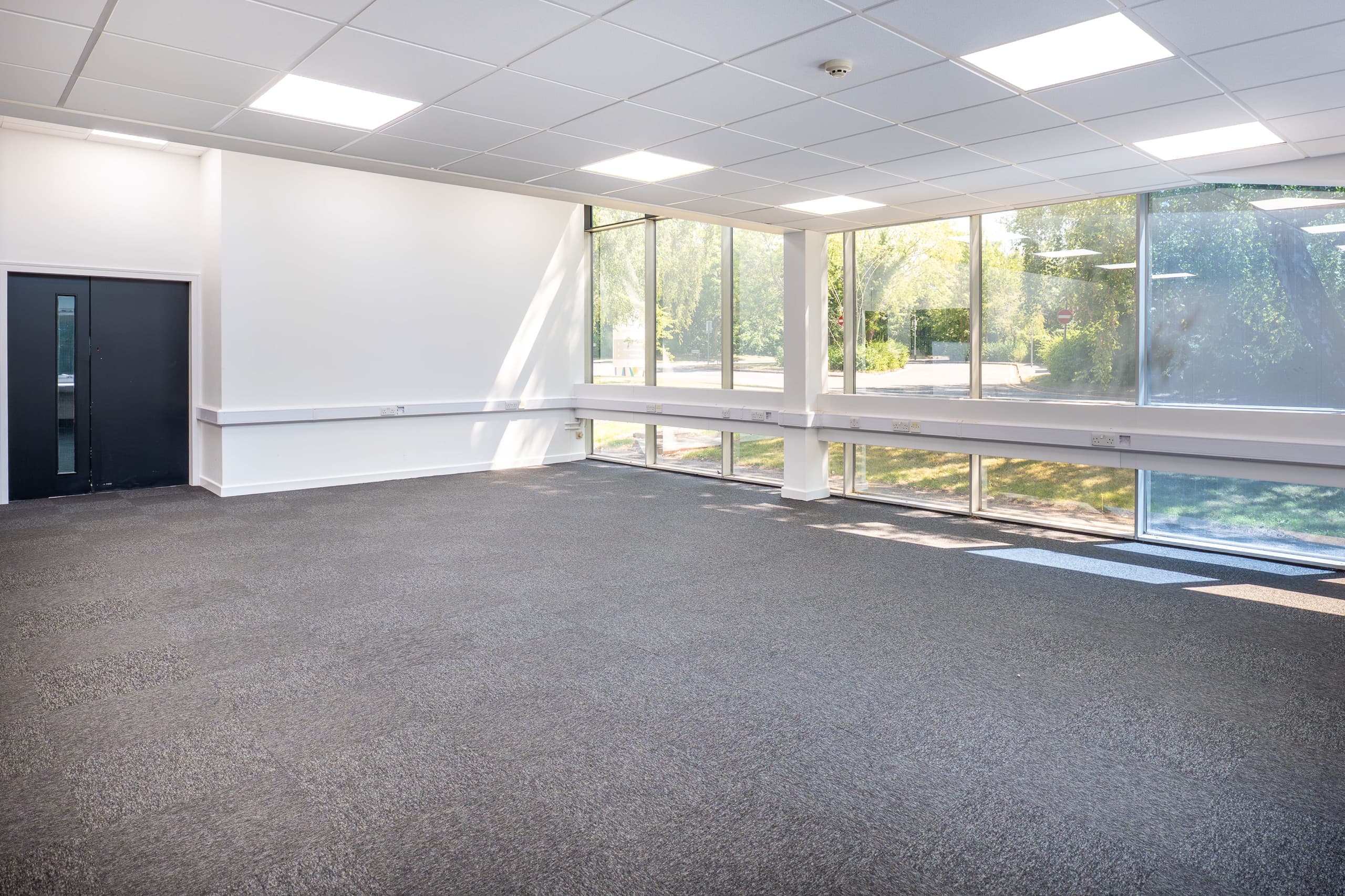 Available corner office suite at Genesis Centre with floor-to-ceiling glass windows overlooking landscaped gardens, Birchwood Warrington