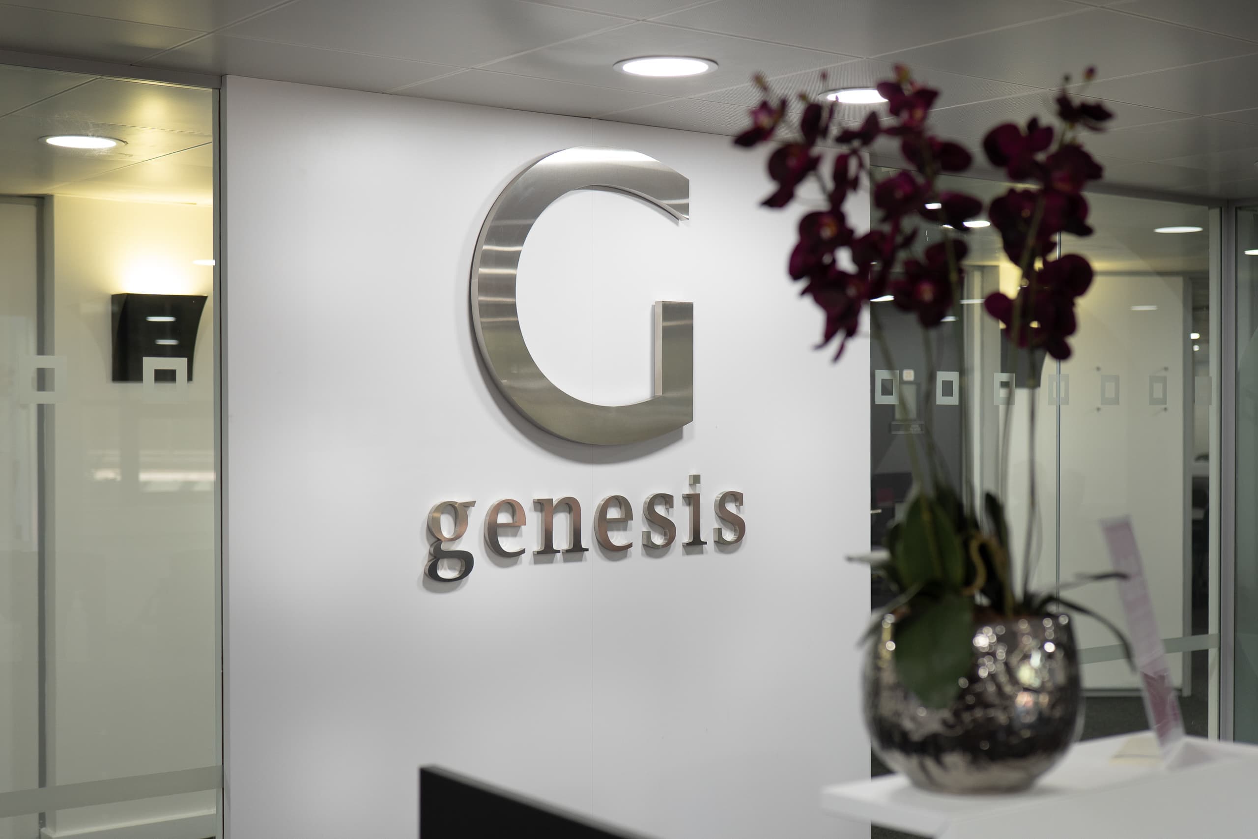 Close-up detail of the Genesis Centre backlit logo on the reception lobby wall, Birchwood Warrington