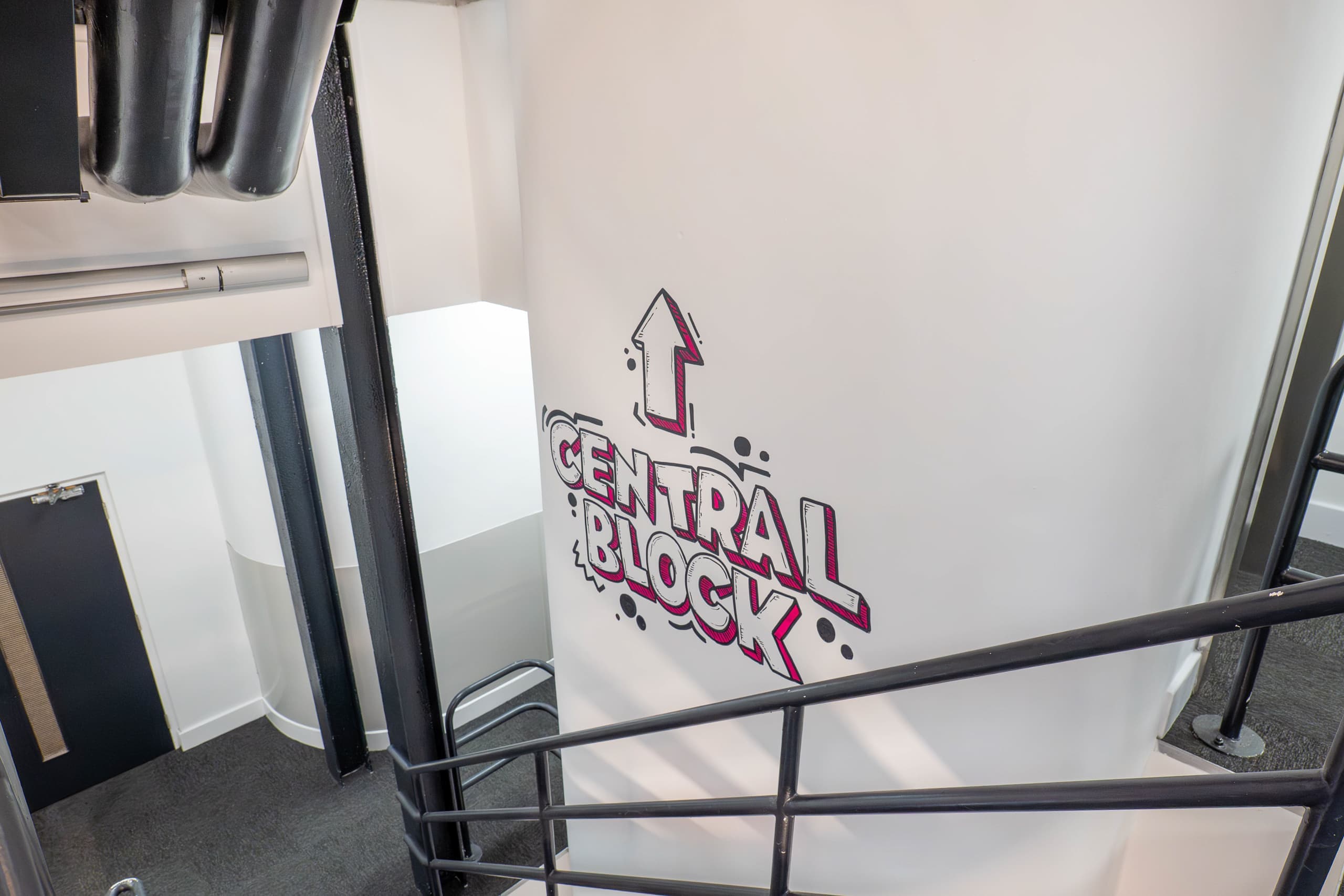 Stairwell at Genesis Centre with CENTRAL BLOCK directional mural in graffiti-style pink and grey lettering, Birchwood Warrington