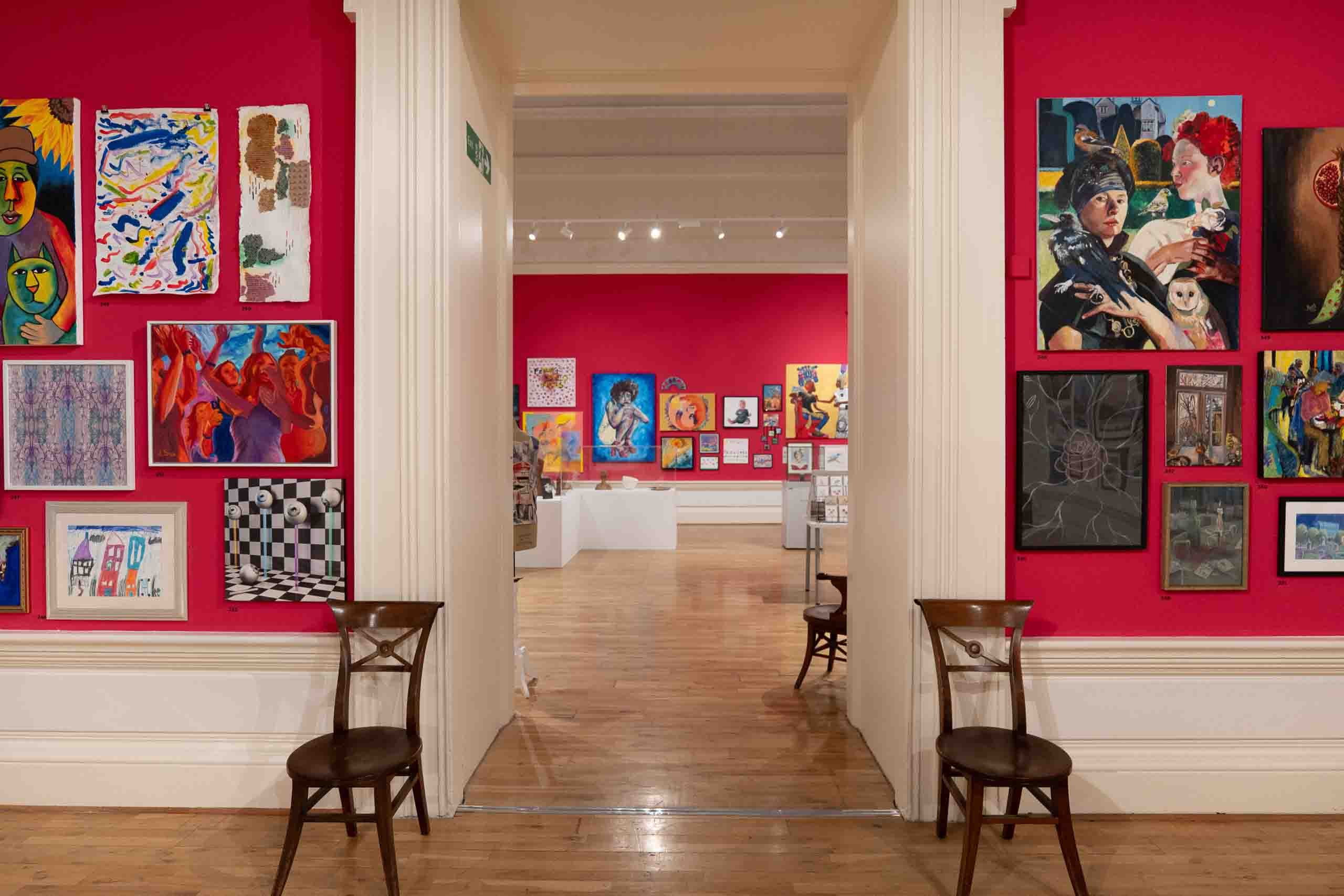 Harris Museum Open Exhibition 2026 Preston — corridor view through gallery doorway with vibrant red walls densely hung with artworks