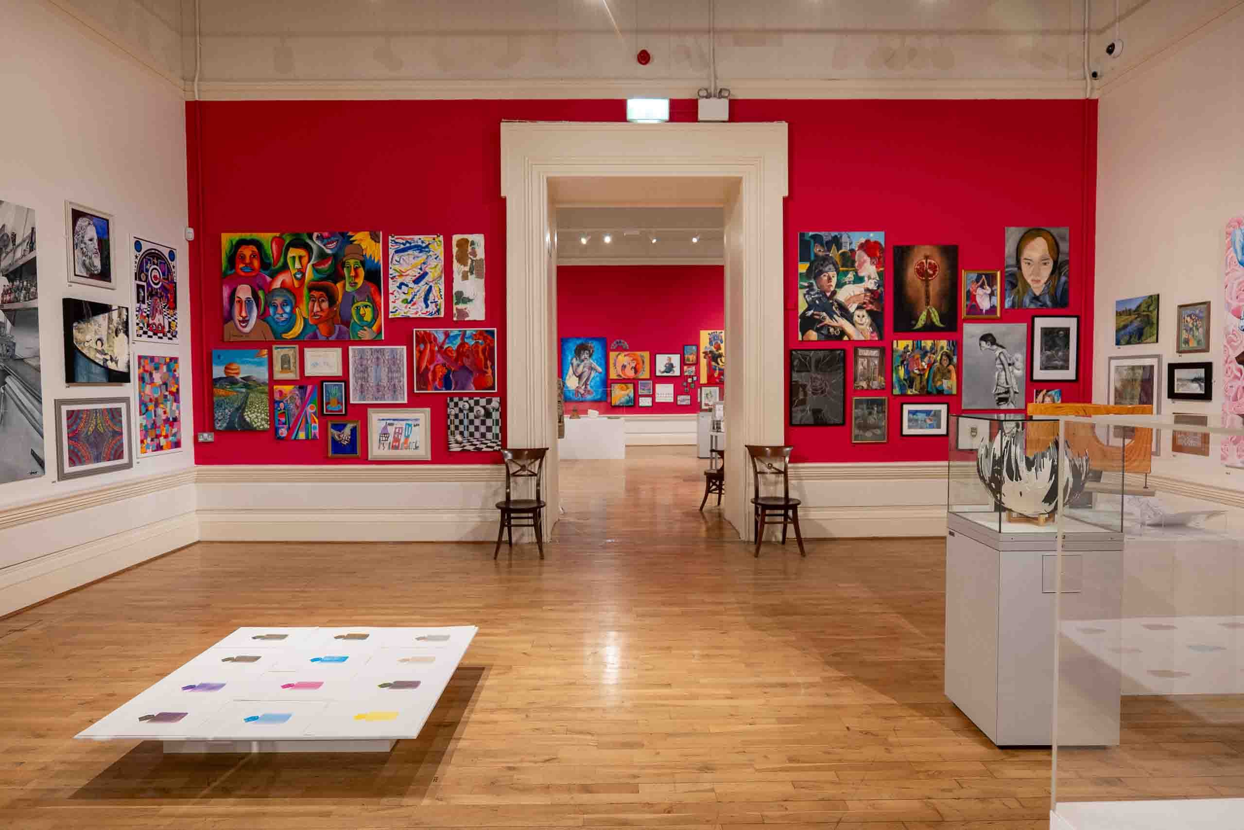Harris Museum Open Exhibition 2026 — wide gallery view featuring white floor installation with colour spots, surrounded by red walls hung with paintings