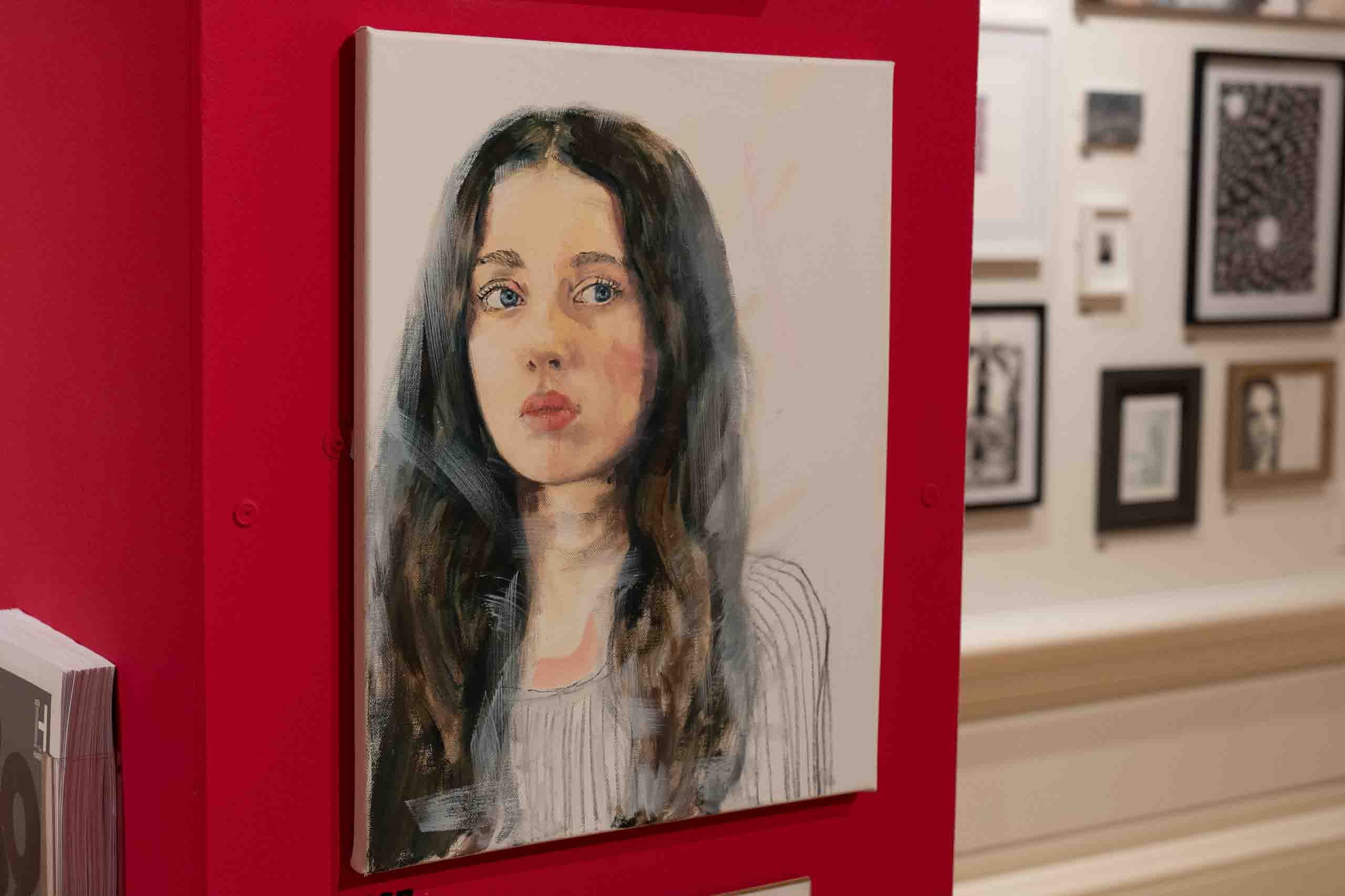 Harris Museum Open Exhibition 2026 — detail of oil portrait painting of a young woman with dark hair displayed on the red feature wall